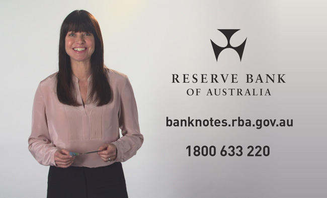 Video still showing a woman with a banknote in hand smiling to the camera.